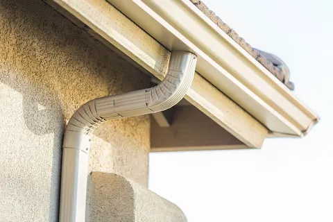 White gutter and downspout on a stone and siding exterior — JR Seamless Gutters, Nashville, TN