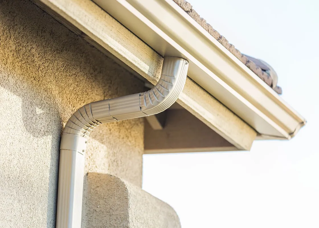 White gutter and downspout on a stone and siding exterior — JR Seamless Gutters, Nashville, TN